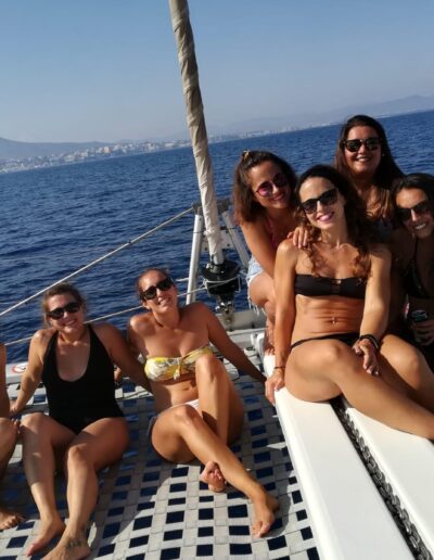Grupo de amigas disfrutando de un paseo en catamarán en Benalmádena, relajándose en la red delantera del barco