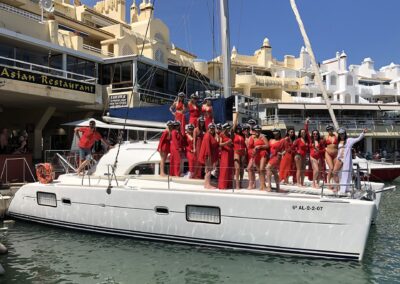 Grupo de chicas vestidas de rojo y la novia de blanco celebrando una despedida de soltera en un barco en Benalmádena