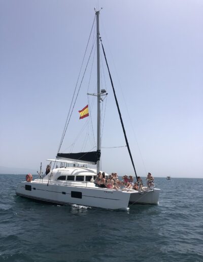People enjoying a catamaran boat ride in Benalmádena, sailing on crystal-clear waters